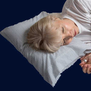 A woman comfortably rests here head on a Pillowpackers inflatable travel pillow